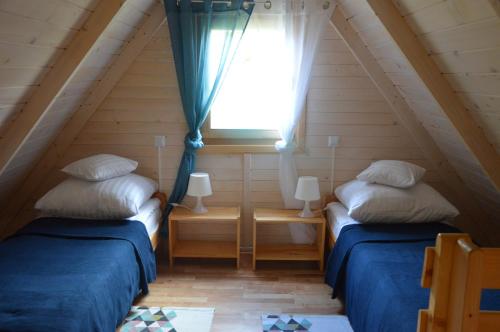 two beds in a small room with a window at Słoneczna Przystań in Sasino