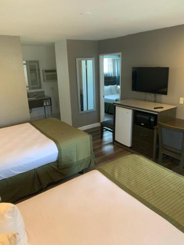 Habitación de hotel con 2 camas y TV de pantalla plana. en Hotel Palmeras Chula Vista, en Chula Vista