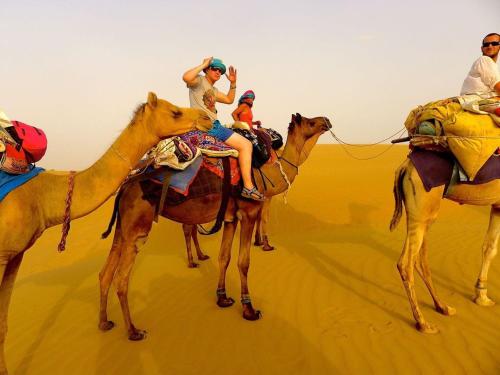 Un gruppo di persone che cavalcano cammelli nel deserto di Sky Desert Safari & Spa a Sām