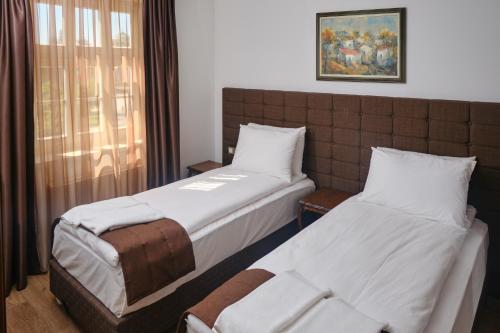 two beds in a hotel room with a window at Hotel Splendid in Pleven