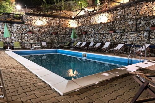 a swimming pool with chairs and a stone wall at Residence SoleNeveSila B&B in Camigliatello Silano