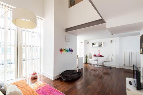 a living room with white walls and a wooden floor at My London Holiday Home in Woolwich