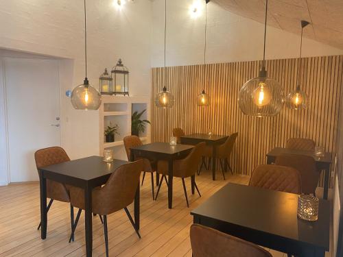 um restaurante com mesas e cadeiras e luzes pendentes em Hotel Sov Godt Herning em Herning