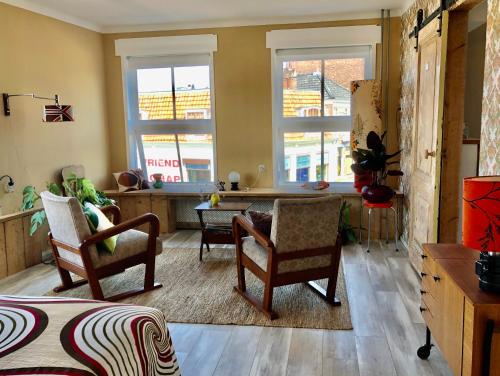 a living room with chairs and a table and windows at Ruime studio 'In de drie koningen' in hartje Middelburg in Middelburg