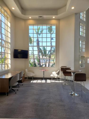 a waiting room with tables and chairs and a large window at Wyndham Garden San Diego in San Diego