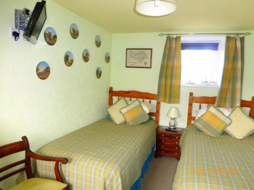 a bedroom with two beds and a tv on the wall at Hazels Roost B&B in Bainbridge