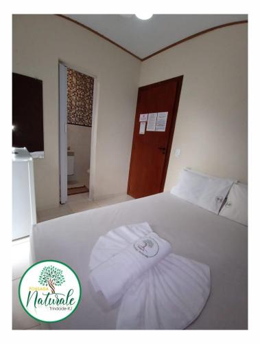 a white bed with a towel on top of it at Pousada Naturale in Trindade