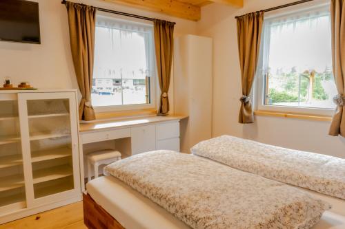 a bedroom with two beds and two windows at BergAufe Chalets Mallnitz in Mallnitz