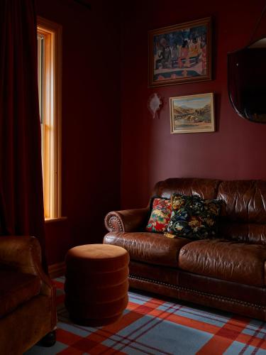 a living room with a brown leather couch and a window at The Dairy Hotel Queenstown, A Naumi Chapter in Queenstown