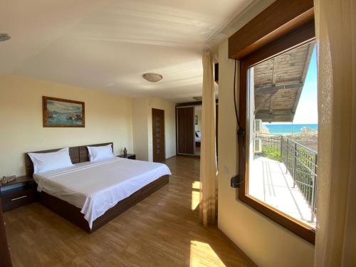a bedroom with a bed and a large window at Casa Andrei in 2 Mai
