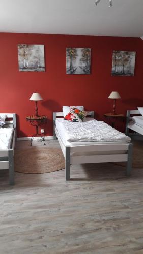 une chambre avec deux lits et un mur rouge dans l'établissement Gite de la Petite Venise du Gatinais, à Pannes