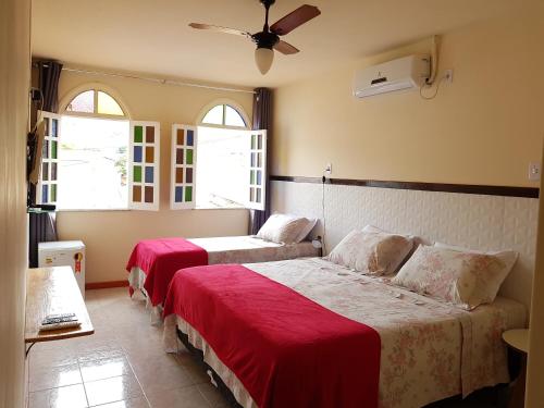 two beds in a room with two windows at Pousada da Villa in Lençóis