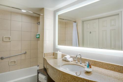 a bathroom with a sink and a mirror and a tub at Crowne Plaza New Orleans French Qtr - Astor by IHG in New Orleans