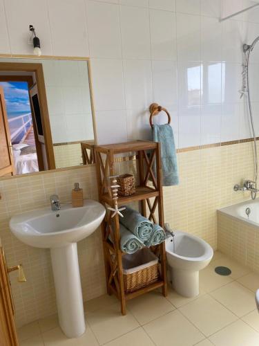 a bathroom with a sink and a toilet and a mirror at Relax en Majanicho sun and stars in La Oliva