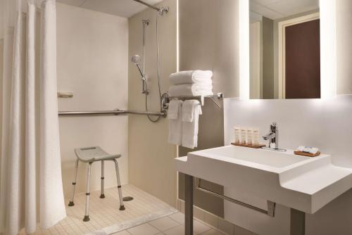 La salle de bains est pourvue d'un lavabo blanc et d'une douche. dans l'établissement Wyndham Garden Conference Center Champaign - Urbana, à Champaign