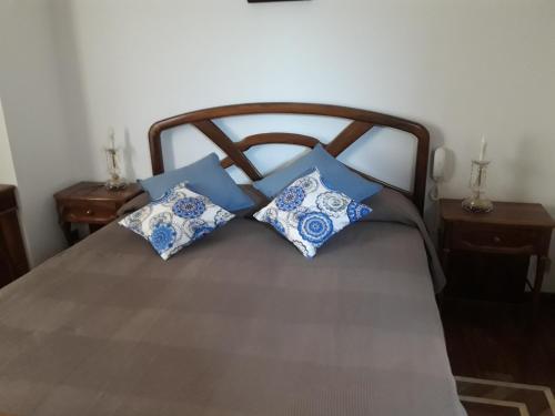Una cama con cuatro almohadas azules y blancas. en Casa NUPI, en SantʼAlessio Siculo