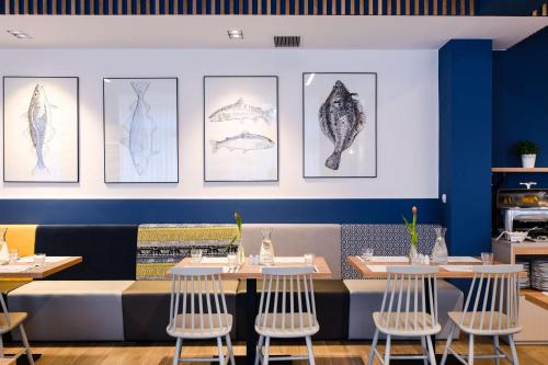 a dining room with tables and drawings on the wall at Best Western Hotel Jurata in Jurata