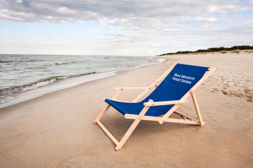 a blue beach chair sitting on the beach at Best Western Hotel Jurata in Jurata