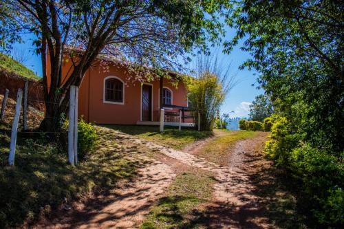 a dirt road leading to a red house at Pousada Sonho Meu in Itanhandu