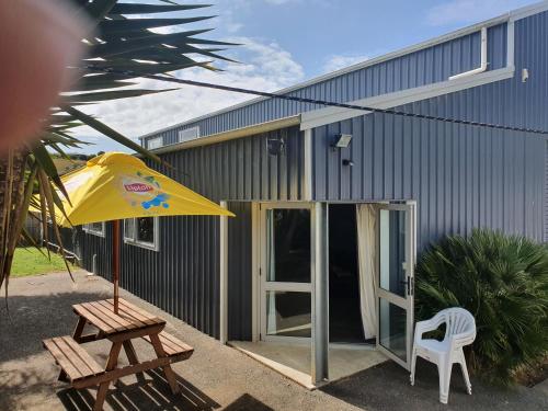 a building with a picnic table and an umbrella at Koromatua Homestead in Whatawhata