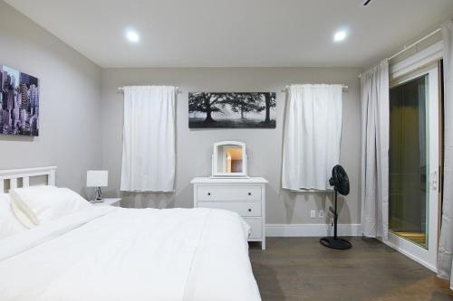 a white bedroom with a white bed and a tv at The Chateau in Burnaby