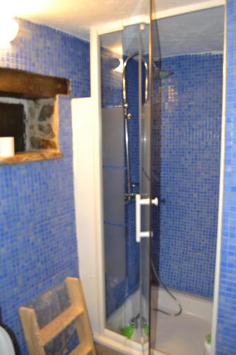 a blue tiled bathroom with a shower with a glass door at Talasnal Montanhas de Amor in Lousã