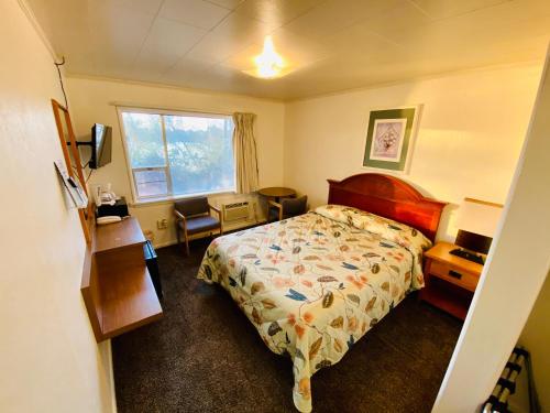 a bedroom with a bed and a desk and a window at Lakeside Motel in Moses Lake