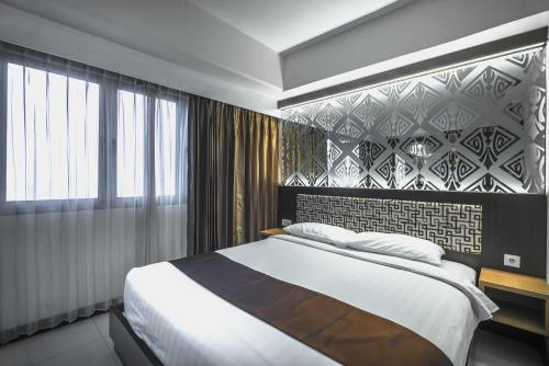 a bedroom with a large bed and a wall at Verwood Hotel and Serviced Residence in Surabaya