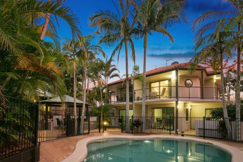 a house with a swimming pool and palm trees at Beaches Apartments Byron Bay in Byron Bay