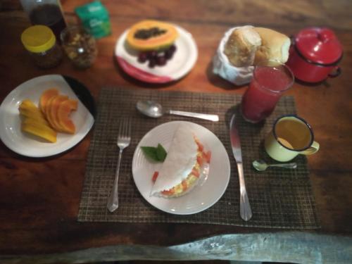 哥隆巴奥Canto de Jurema Corumbau Glamping, Chalé, Acolhimento e Sustentabilidade的一张木桌,上面放有食物和餐具