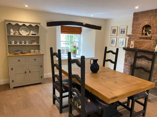 a dining room with a wooden table and a kitchen at The Cosy Nook Cottage Company - Cosy Cottage in Warcop