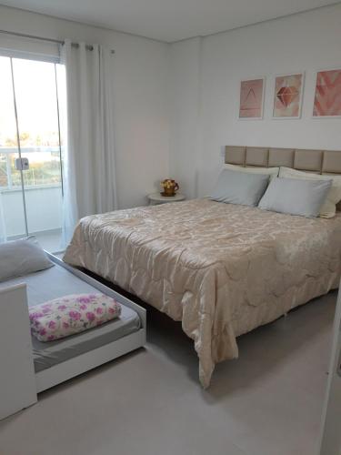 um quarto branco com uma cama grande e uma janela em Apartamento com vista pro mar próximo ao Beto Carrero em Penha