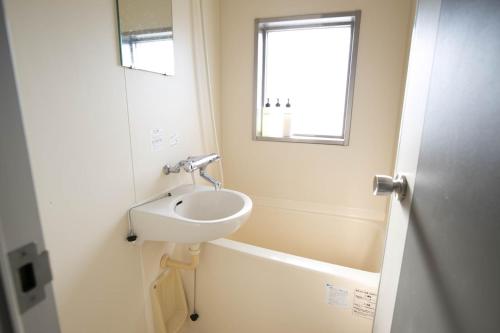 a bathroom with a sink and a window at SUMIYOSHI APARTMENT Hotel 住吉アパートメントホテル in Fukuoka