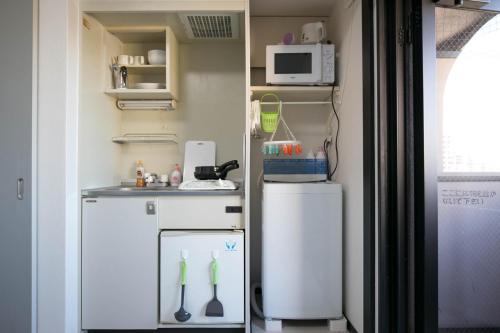 a small kitchen with a refrigerator and a microwave at SUMIYOSHI APARTMENT Hotel 住吉アパートメントホテル in Fukuoka