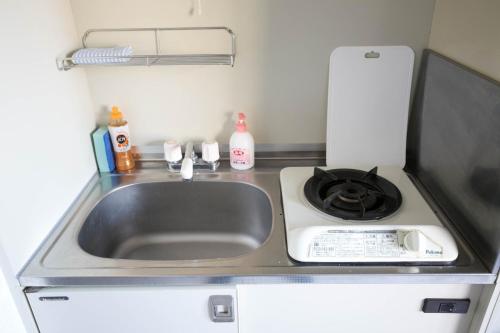 a kitchen counter with a sink and a stove at SUMIYOSHI APARTMENT Hotel 住吉アパートメントホテル in Fukuoka