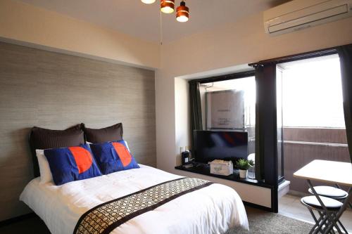 a bedroom with a bed and a tv and a window at SUMIYOSHI APARTMENT Hotel 住吉アパートメントホテル in Fukuoka