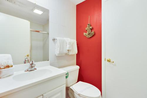 uma casa de banho com um WC branco e uma parede vermelha em Anna Maria's Finest em Anna Maria