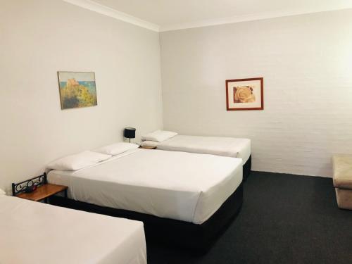 a hotel room with two beds and a couch at Campbelltown Colonial Motor Inn in Campbelltown