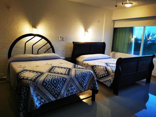a bedroom with two beds and a window at Suites Brisas Cancun in Cancún