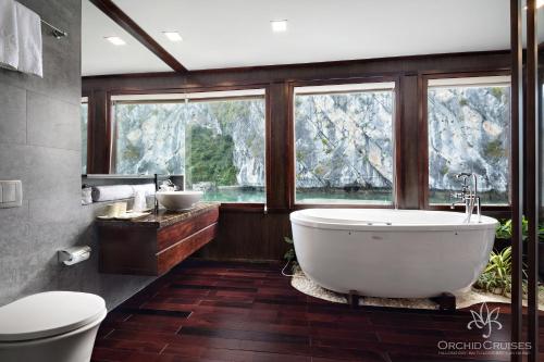 La salle de bains est pourvue d'une grande baignoire et d'une fenêtre. dans l'établissement Orchid Classic Cruise, à Hạ Long
