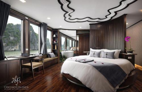 a bedroom with a large bed and a desk and a room withwindows at Orchid Classic Cruise in Ha Long