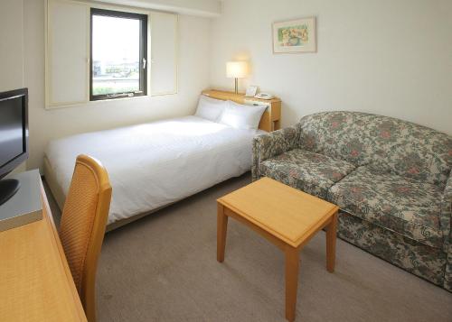 a hotel room with a bed and a couch at Smile Hotel Fukuoka Okawa in Ōkawa