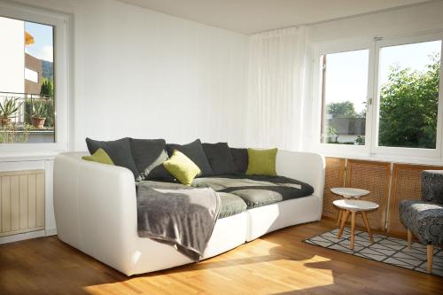 a white couch in a living room with windows at Haus Bregenz Apartment Bodensee in Lochau