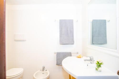 a white bathroom with a sink and a toilet at Appartamento del Cormorano in Olbia