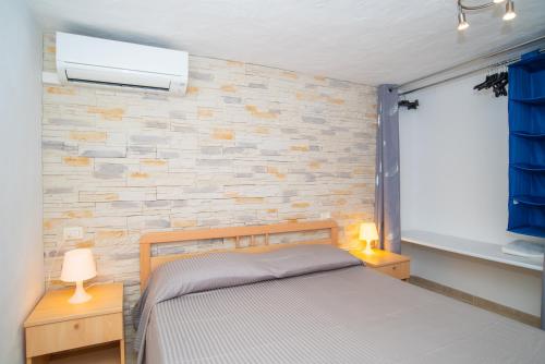a bedroom with a bed and a brick wall at Appartamento del Cormorano in Olbia
