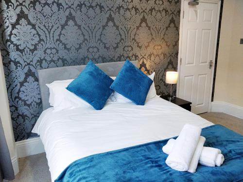 Una cama con almohadas azules y blancas. en Lyndhurst House en Luton