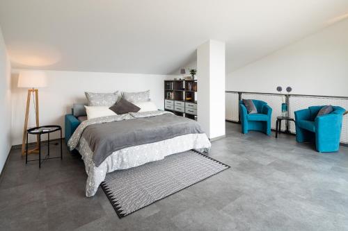 ein Schlafzimmer mit einem Bett und zwei blauen Stühlen in der Unterkunft Ferienhaus Altstadtblick Bad Wildungen in Bad Wildungen