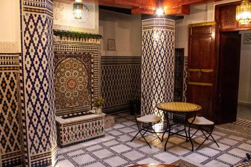 um quarto com uma mesa e cadeiras e um piso de azulejo em Dar Lantana em Fez