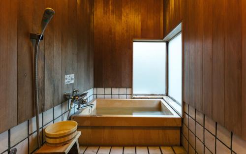 a bathroom with a tub and a toilet and a window at Futsukaichi Hot Spring - Daimaru Besso in Chikushino