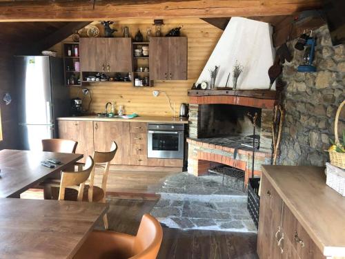 a kitchen with a stone fireplace and wooden cabinets at Къща за гости Виевци in Vievo